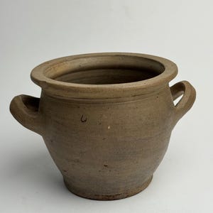May include: A trio of ceramic mugs with a speckled, matte finish in cream, light grey, and dark grey. Each mug features a simple, minimalist design, ideal for tea or coffee.