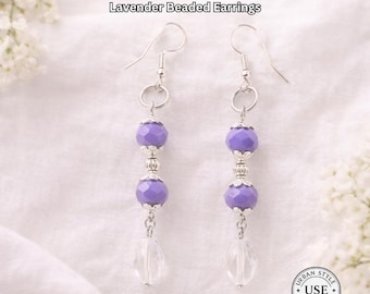May include: Lavender beaded earrings with faceted purple beads and clear teardrop-shaped pendants. The earrings have silver-colored metal accents and ear wires. The text "URBAN STYLE ESSENTIALS" and "Lavender Beaded Earrings" are at the top of the image.