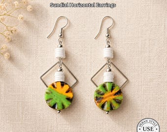 May include: A pair of Sundial Horizontal Earrings. Each earring features a silver hook, white beads, a silver square, and a circular pendant with green, yellow, and brown patterns. The text "URBAN STYLE ESSENTIALS" is at the top and bottom.