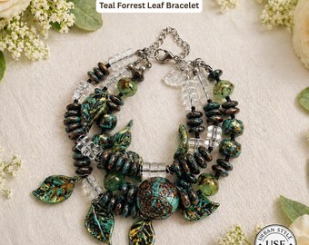 May include: A teal and green beaded bracelet with leaf accents. The bracelet features a mix of round and leaf-shaped beads, clear crystal beads, and a silver chain clasp. The text "Urban Style Essentials" and "Teal Forrest Leaf Bracelet" are visible.