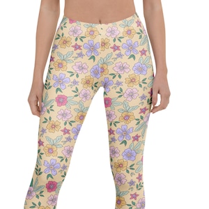 May include: Full-length leggings featuring a light yellow background with a repeating floral pattern in shades of purple, pink, and orange with green leaves. Text on the left reads: FLUTTER PIXIE ART, SHORTS, CAPRI, LEGGINGS, PLUS SIZE LEGGINGS, YOGA SHORTS, YOGA CAPRI, YOGA LEGGINGS, YOUTH LEGGINGS, KIDS LEGGINGS.
