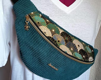 Peut inclure: Un sac banane en velours côtelé bleu sarcelle avec un panneau diagonal à motif floral multicolore dans des tons de vert, doré et noir. Le sac comprend une fermeture éclair dorée avec une breloque fleur et une petite plaque logo en métal doré.