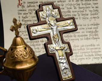 May include: A detailed wooden cross with silver and gold accents, depicting Jesus Christ on the cross. The cross has a dark brown border and intricate carvings. The background includes an antique document and a golden censer.