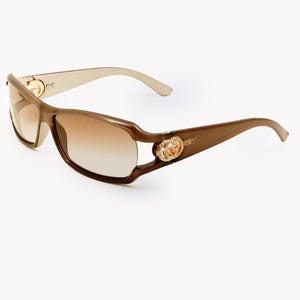 May include: Brown sunglasses with a gradient lens. The frames are a darker brown with gold-colored accents on the temples and arms. The lenses transition from a darker shade at the top to a lighter shade at the bottom.