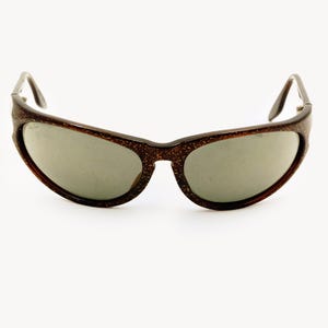 May include: Brown speckled sunglasses with gray lenses. The sunglasses have a curved frame and dark brown arms. The lenses are oval-shaped and the frame has a speckled pattern.