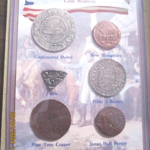 May include: A collection of coin replicas from the 1776 American Revolution, including a Continental Dollar, New Hampshire coin, 2-Bits, Pillar 4 Reales, Pine Tree Copper, and Janus Half Penny. The coins are displayed in a clear plastic case.