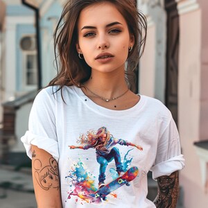 May include: White t-shirt with a colorful graphic print of a woman skateboarding. The graphic features splashes of blue, yellow, orange, pink, and green paint.