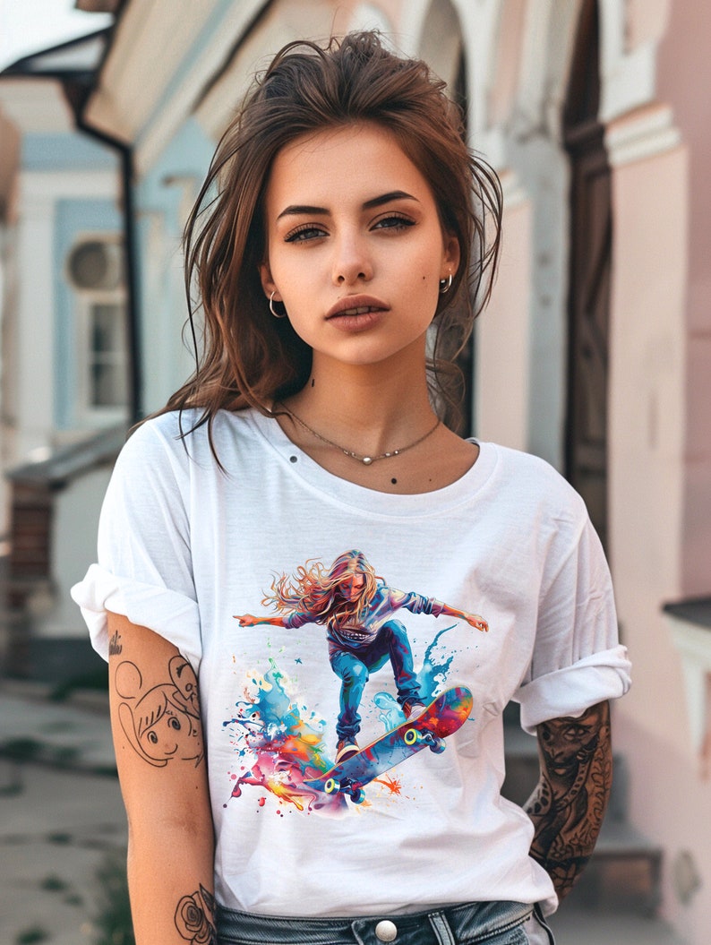 May include: White t-shirt with a colorful graphic print of a woman skateboarding. The graphic features splashes of blue, yellow, orange, pink, and green paint.