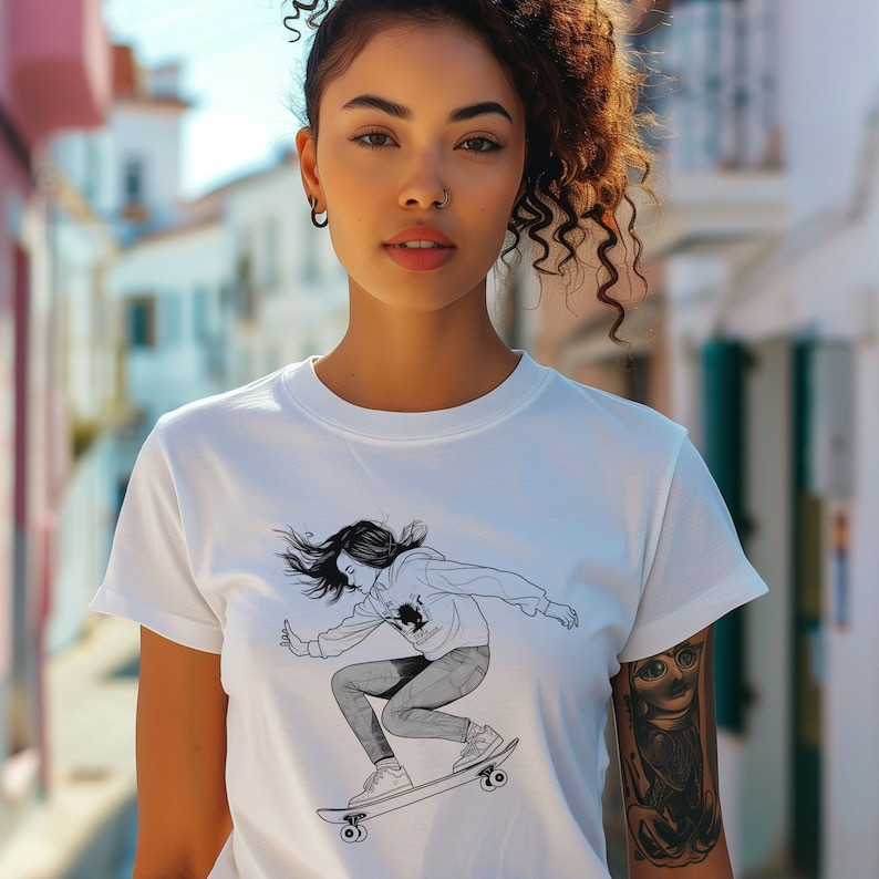 May include: A white t-shirt with a black and white illustration of a woman skateboarding. The woman is wearing a hoodie and jeans.