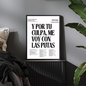 May include: A black framed poster with white text that reads "Y POR TU CULPA, ME VOY CON LAS PUTAS". The poster is displayed on a black dresser. The room has a grey wall, a black light fixture, and a large green plant.