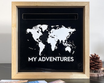 May include: A wooden shadow box with a black background featuring a white outline of a world map and the text "MY ADVENTURES". The box is open and there are three photos inside.
