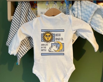 Ropa infantil única Beck and Co. Diseño Sol y Luna disponible como mono o camiseta para bebé, colores personalizables, desde recién nacido hasta los 5 años