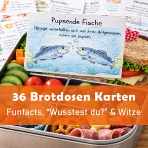 Puede incluir: Una lonchera llena de verduras frescas, un sándwich y otros bocadillos. Una tarjeta con el texto "Pupsende Fische" y una ilustración de dos peces está dentro de la lonchera. El texto "36 Brotdosen Karten" también es visible.