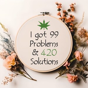May include: A white embroidery hoop with a green marijuana leaf design and the text "I got 99 Problems & 420 Solutions".