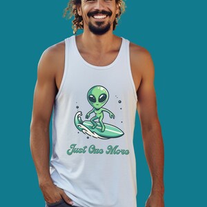 May include: A white tank top with a green alien cartoon character surfing on a wave. The text "Just One More" is printed below the alien.