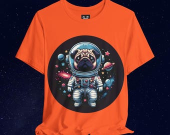 May include: Orange t-shirt with a circular graphic of a pug wearing an astronaut suit in space. The pug is surrounded by stars, planets, and a galaxy.