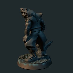 May include: A gray, 3D printed miniature figurine of a shark-like humanoid creature. The figure is standing on a round base with a textured surface. The creature has a humanoid body with a shark head and tail.