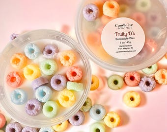 May include: A clear plastic container filled with colorful, donut-shaped wax melts. The container has a white label that reads "Fruity O's Scoopable Wax 5 oz/141g Handmade in Fort Wayne, IN candleliteaesthetics.com".
