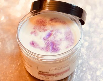 May include: A clear jar with a black lid filled with a white body butter. The body butter has a purple shimmer and the jar has a label that reads "queen Craft Essentials Body Butter Royally Radiant 8 oz | 226g".