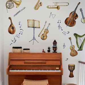 Puede incluir: Una pared blanca con calcomanías de instrumentos musicales, que incluyen un violín, un arpa, una guitarra, un violonchelo, una trompeta, una flauta, un saxofón y una mandolina. También hay notas musicales y un atril de música. Un piano marrón se encuentra frente a la pared.