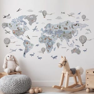 Könnte beinhalten: Eine dekorative Weltkarte als Wandaufkleber in Blau und Grau, verziert mit Illustrationen von Tieren, Flugzeugen und Heißluftballons. Ein Plüschhase, ein Schaukelpferd aus Holz und ein Hocker mit grau-weißem Muster befinden sich im Vordergrund.