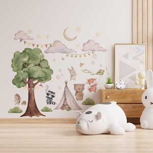 Puede incluir: Un conjunto de calcomanías de pared caprichosas con un tema de bosque. El diseño incluye un árbol grande, nubes, estrellas, una luna creciente y varios animales como un mapache, un zorro, un oso y un conejo. También se incluye un tipi y una cometa. La paleta de colores es suave y pastel.