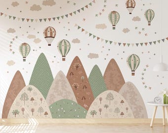 May include: A white wall mural with a whimsical design featuring green and brown mountains, colourful hot air balloons, and a string of flags. The mountains are layered and have a textured pattern. The hot air balloons are in various colours and sizes, and some have stars around them. The flags are in shades of pink, brown, and grey.