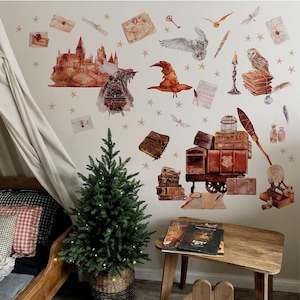 May include: A whimsical wall decal set featuring a castle, train, owl, and other magical elements. The set includes a sorting hat, books, and a stack of luggage. A small Christmas tree is in the foreground, and a wooden table with books is in the foreground.