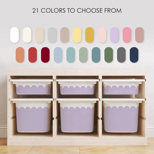 May include: A light-colored wooden storage unit featuring six white bins with lavender scalloped edges. Above the unit, a color chart displays 21 distinct oval color swatches with the text 21 COLORS TO CHOOSE FROM centered at the top.