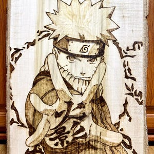 May include: A wood-burned image of Naruto Uzumaki, a popular anime character, with his signature headband and a swirling background. The image is burned into a light brown wooden surface.