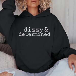 May include: A black hooded sweatshirt with the text "dizzy & determined" in white lettering.