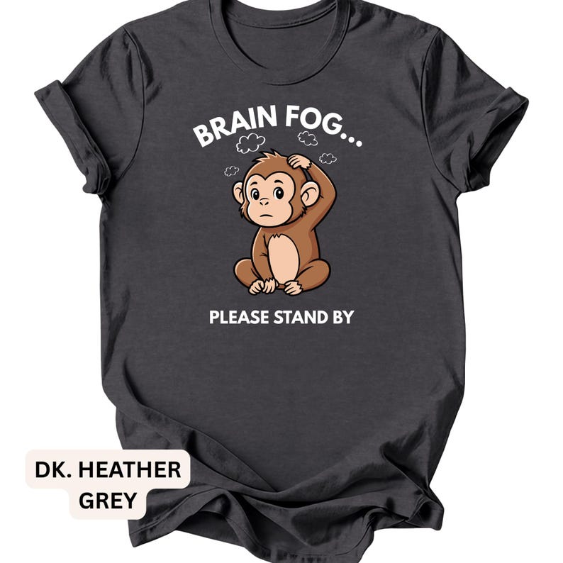 Puede incluir: Camiseta gris jaspeado oscuro con un mono de dibujos animados y el texto "BRAIN FOG... PLEASE STAND BY". El mono marr&oacute;n parece confundido. La camiseta tiene cuello redondo.