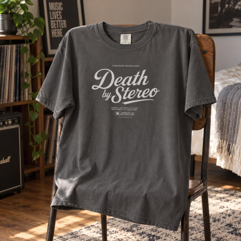 A dark charcoal grey t-shirt with Death by Stereo text draped over a wooden chair.