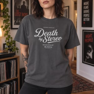 A person wearing a dark charcoal grey t-shirt featuring a white Death by Stereo movie graphic.
