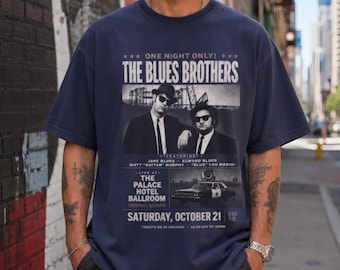 May include: Navy blue t-shirt featuring a black and white image of The Blues Brothers. The graphic includes the text "ONE NIGHT ONLY!" and "THE BLUES BROTHERS". Additional text includes "LIVE AT THE PALACE HOTEL BALLROOM" and "SATURDAY, OCTOBER 21".