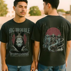 Puede incluir: Camiseta verde oscuro con el texto "BIG TROUBLE IN LITTLE CHINA" y gráficos en la parte delantera y trasera. La parte delantera presenta un personaje y texto en idioma extranjero, la trasera muestra un grupo de figuras.
