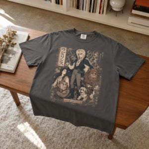 A man wears a black t-shirt with a graphic of Jareth the Goblin King, Sarah, Hoggle, Ludo, and Sir Didymus in a Japanese poster art style, with Japanese text on the left.