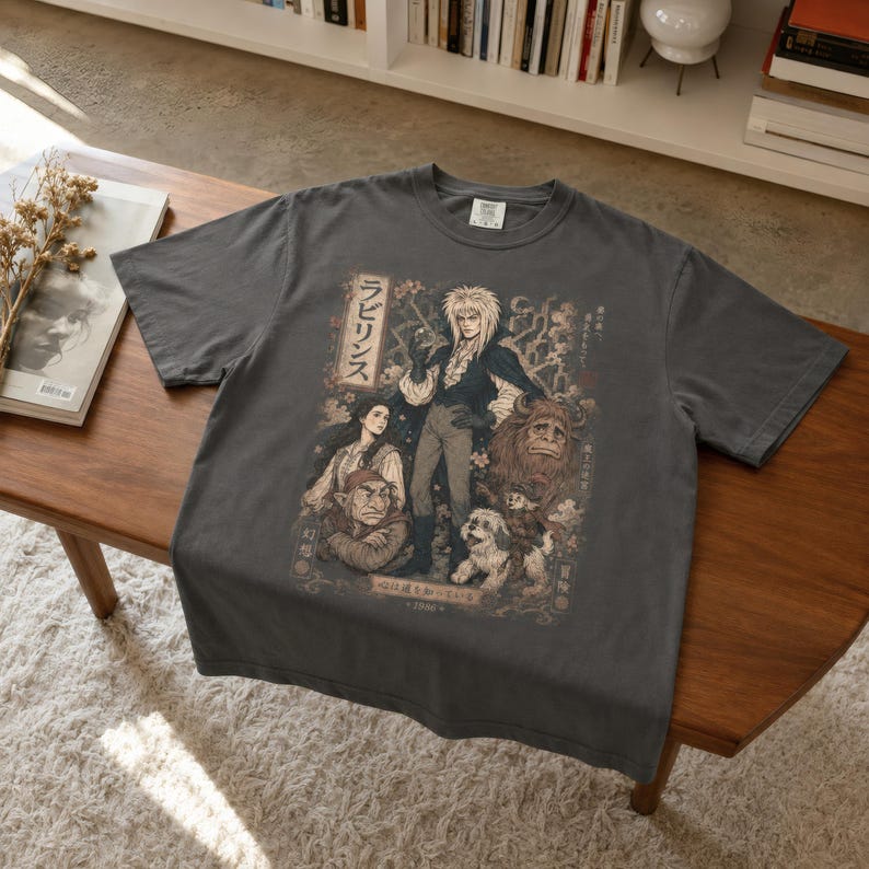 A man wears a black t-shirt with a graphic of Jareth the Goblin King, Sarah, Hoggle, Ludo, and Sir Didymus in a Japanese poster art style, with Japanese text on the left.