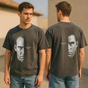 Peut inclure: T-shirts gris foncé avec un graphisme de visage divisé en deux. L'un des t-shirts montre Sean Archer, Face Off, et l'autre Castor Troy, Face Off. Les t-shirts sont portés par une personne.