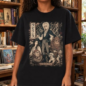 A woman wears a white t-shirt with a graphic of Jareth the Goblin King, Sarah, Hoggle, Ludo, and Sir Didymus in a Japanese poster art style, with Japanese text on the left.