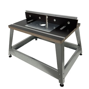 May include: A router table with a black top and a silver metal frame. The table has a router insert plate and a fence with a sliding track.