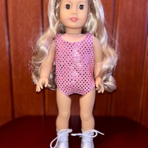 May include: A doll with long blonde hair wearing a pink sequined leotard and silver boots.