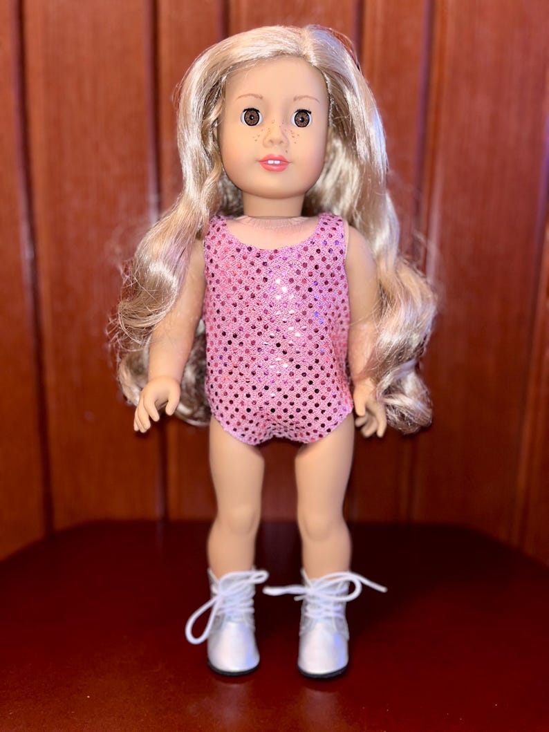 May include: A doll with long blonde hair wearing a pink sequined leotard and silver boots.