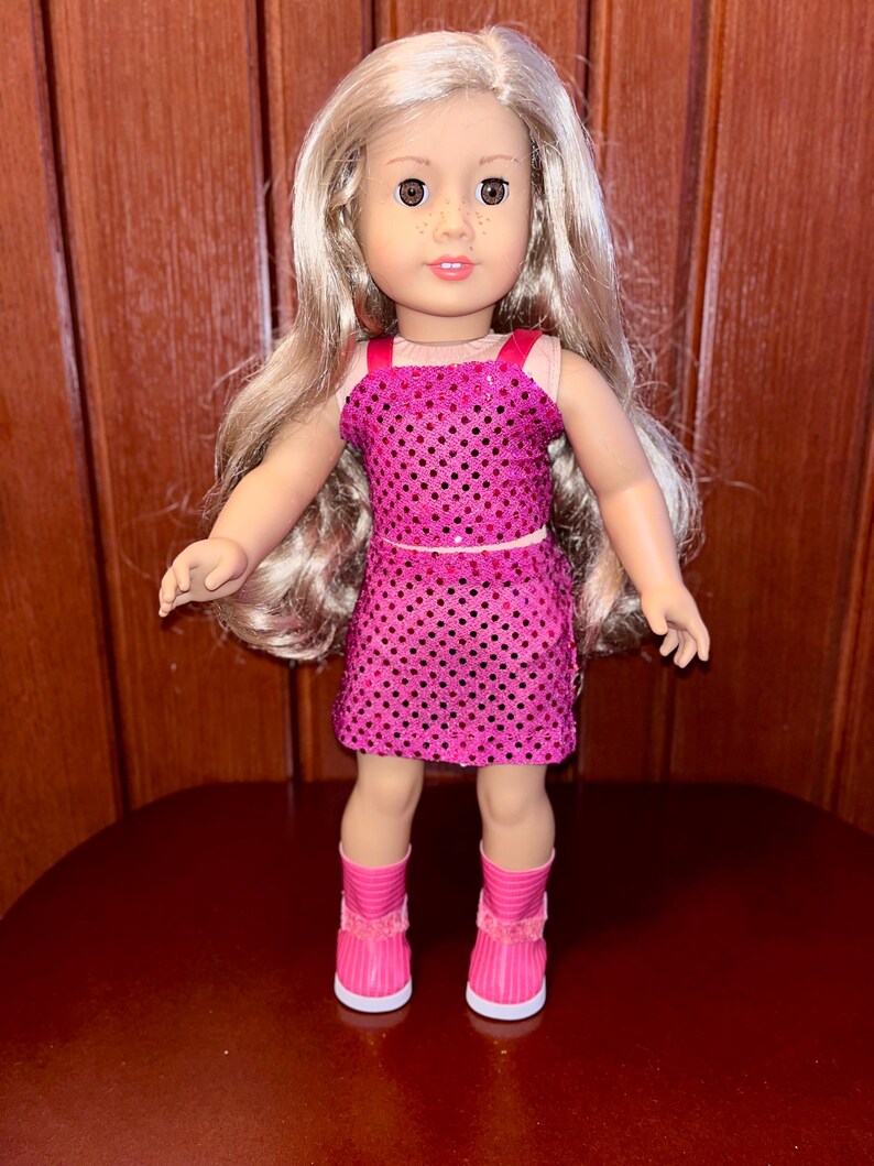 May include: A doll with long blonde hair wearing a pink sequined dress and pink boots.