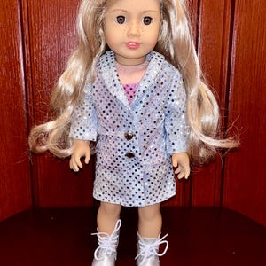 May include: A doll wearing a silver sequined dress and silver boots. The doll has blonde hair and brown eyes.