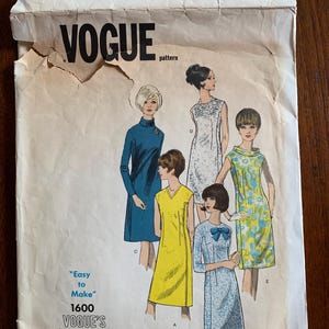 May include: Vintage Vogue sewing pattern envelope featuring illustrations of five different dresses. The envelope is off-white with the Vogue logo and text "Easy to Make" and "Vogue's Basic Dress". The dresses are in various colors and styles.