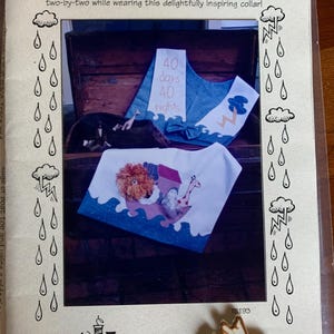 May include: A sewing pattern titled "TWO by TWO COLLAR" with illustrations of collars. One collar features a lion, giraffe, and other animals on an ark. The text "40 days 40 nights" is also visible. A button in the shape of a dove is in the lower right corner.