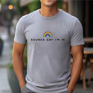 K&ouml;nnte beinhalten: Ein graues T-Shirt mit einem Regenbogen-Motiv und dem Text "SOUNDS GAY I'M IN".