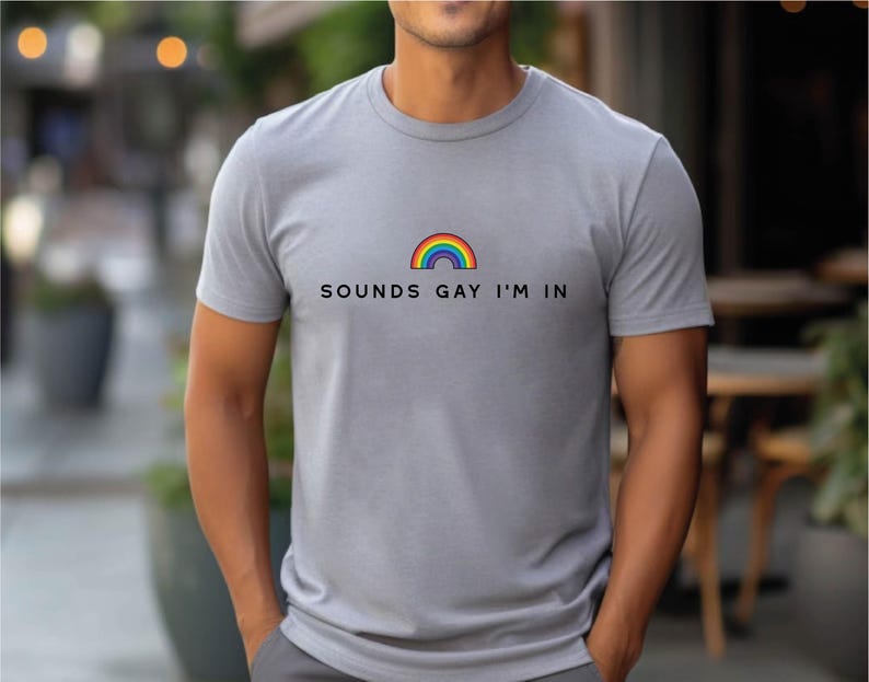 K&ouml;nnte beinhalten: Ein graues T-Shirt mit einem Regenbogen-Motiv und dem Text "SOUNDS GAY I'M IN".