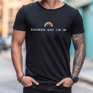 K&ouml;nnte beinhalten: Ein schwarzes T-Shirt mit einem Regenbogen-Motiv und dem Text "SOUNDS GAY I'M IN".
